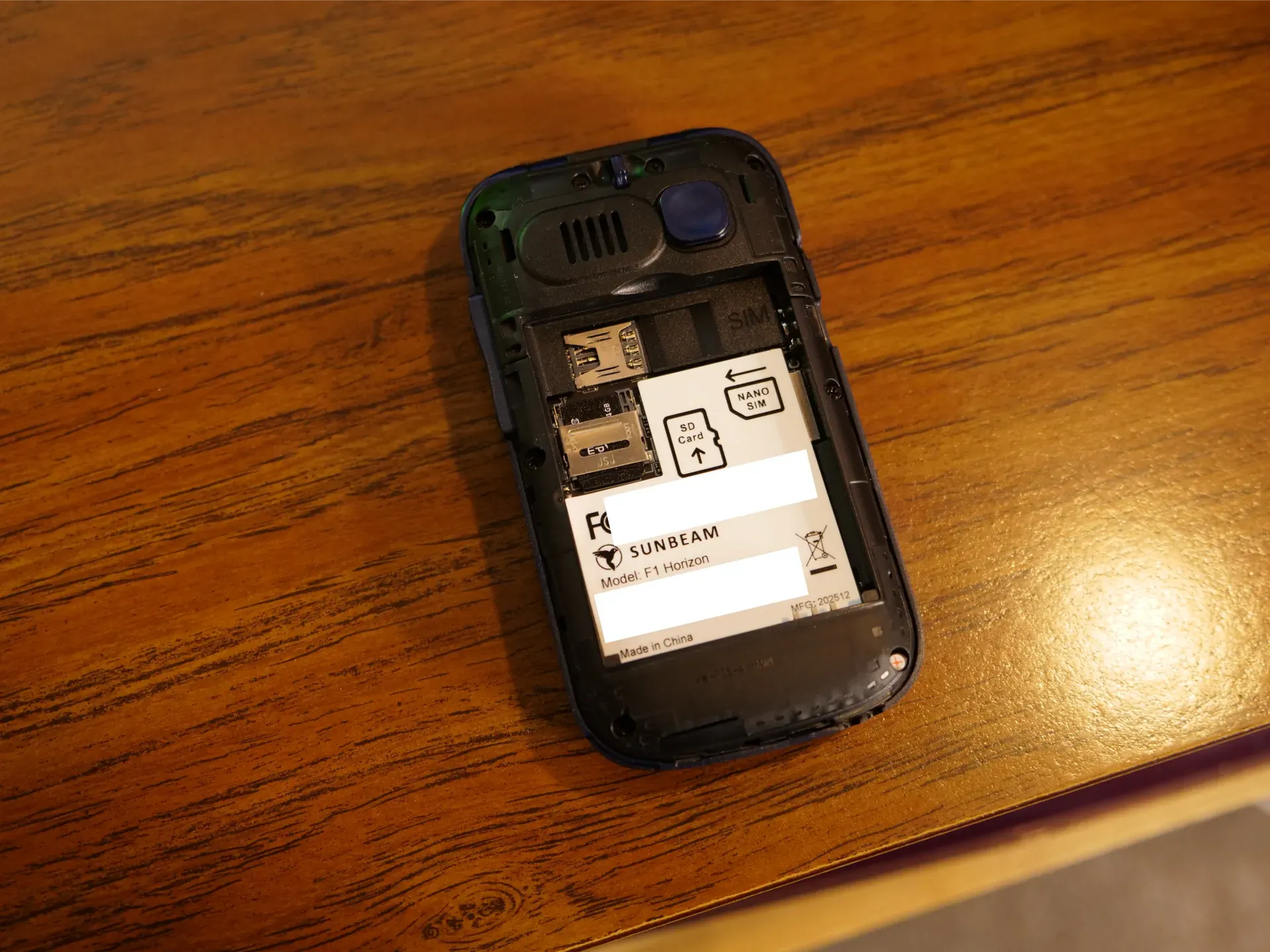 A dumbphone with the back taken off, showing a spot for a nano SIM and a Micro SD card. The brand is "Sunbeam".